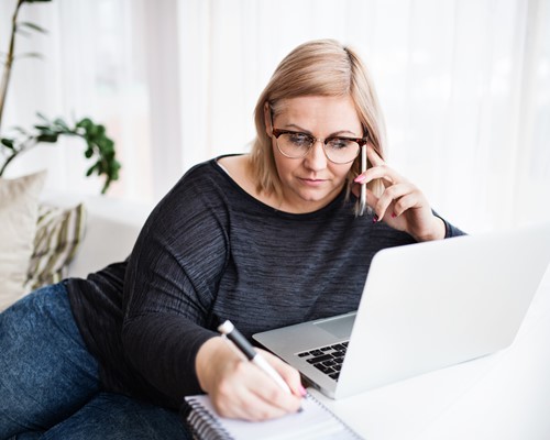 Woman on phone and laptop trying to manage her debt