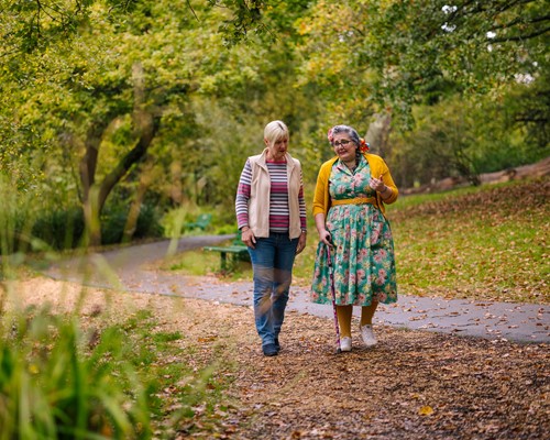Two women talking and walking in a woodland setting