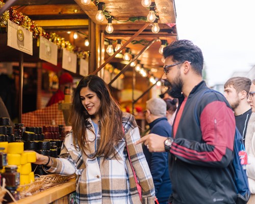 Asian man and woman looking at items on a food stall 