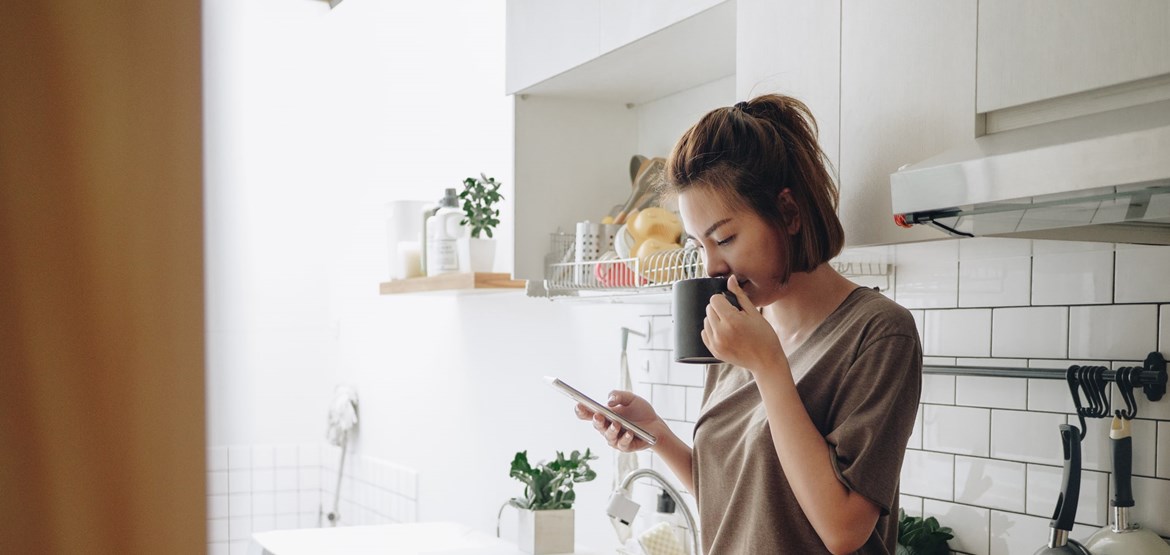 Woman drinking coffee and looking at phone