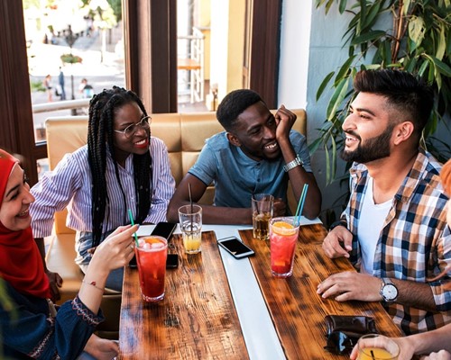 Group of young people talking around a table with soft drinks