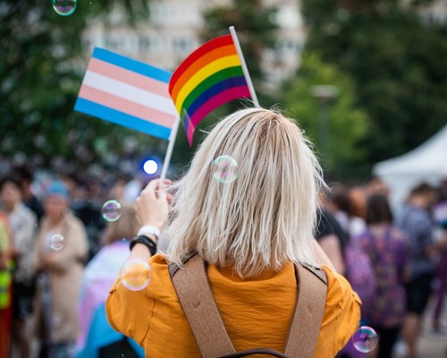 Woman holding Pride and Trans flags