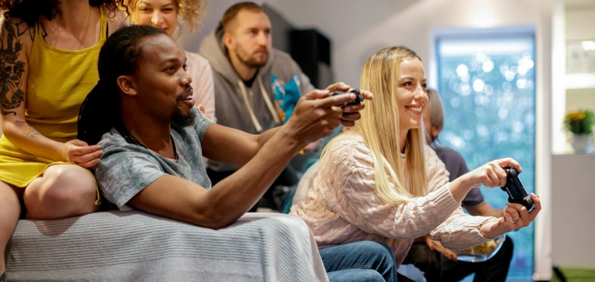 Group of people sat on sofa playin video games
