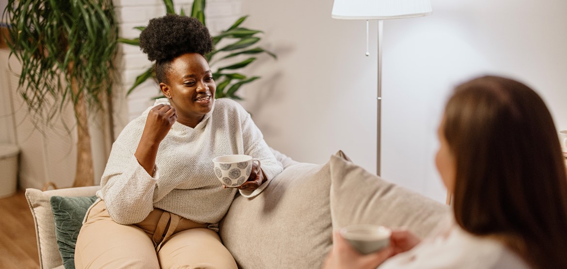 Two friends chatting on the sofa at home