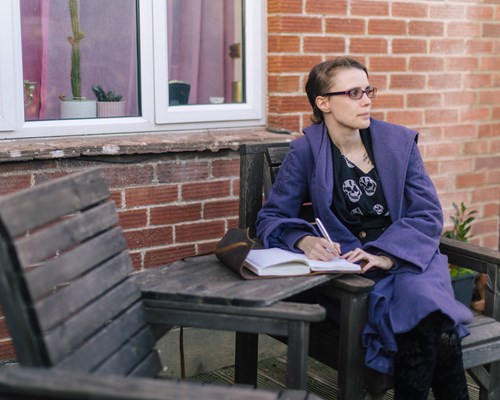 Woman sat on bench with notebook