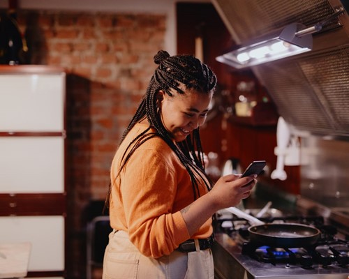 Woman checking phone while cooking