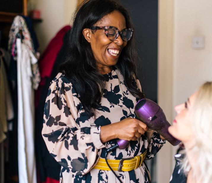 Person with hairdryer smiling at friend.
