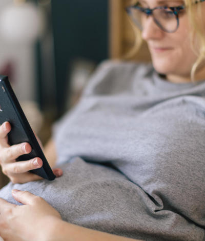 Woman resting in bed on her phone