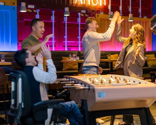 Friends high-fiving and playing table football.