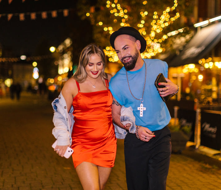 Two friends joyfully walking down a night time street