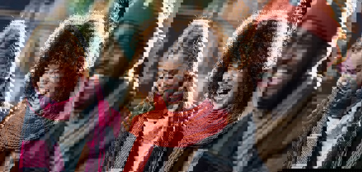 Three people in a row laughing dressed in winter clothes