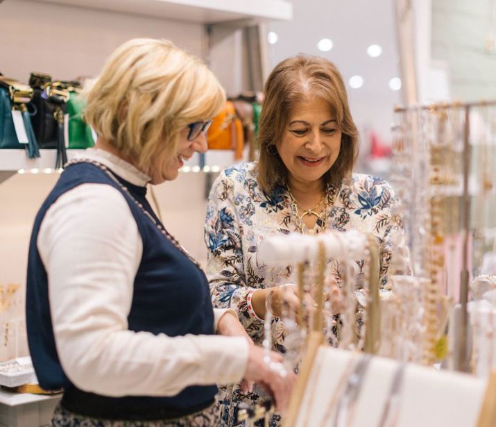 Two people looking at necklaces in boutique shop.