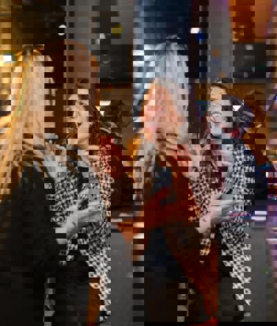 A couple of women talking and laughing at a high table in a social setting