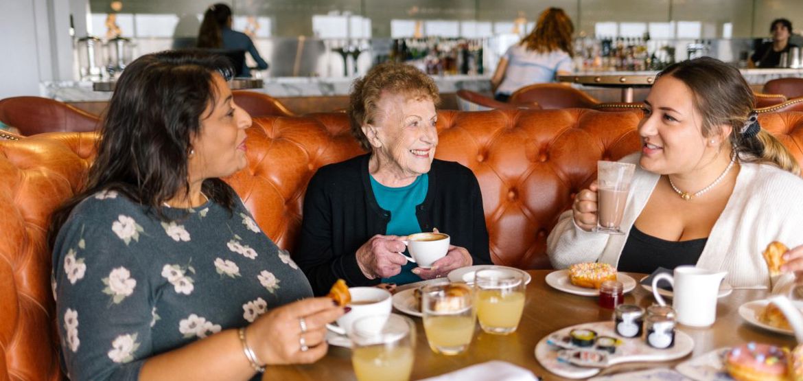 Three people having coffees and pastries in restaurant.