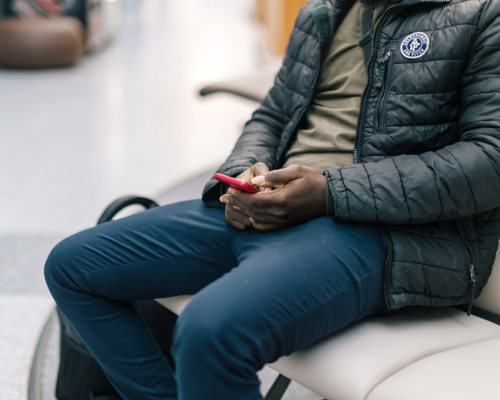 A person sitting on a seat in a corridor looking at their phone