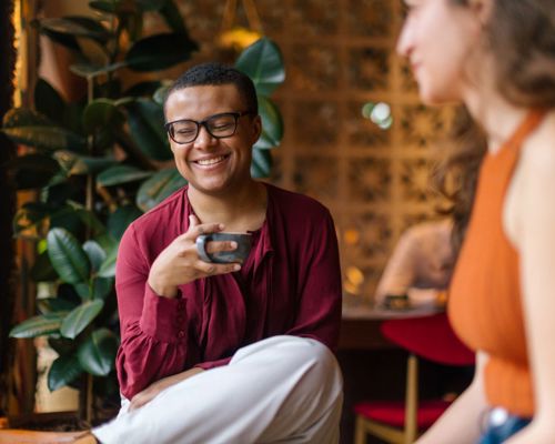 Person smiling and holding coffee cup.