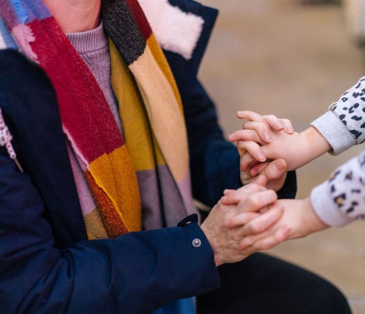 Close up of adult holding hands with child.