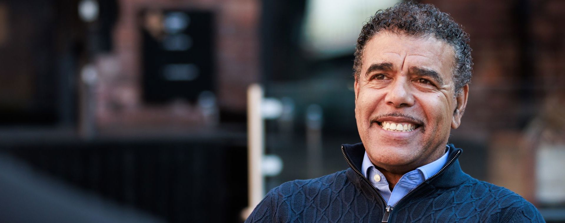 Ex- footballer Chris Kamara smiling while listening to another person talk