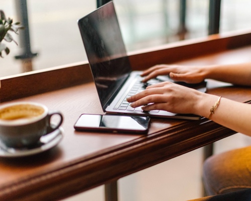 Woman writing on her laptop in a coffee shop