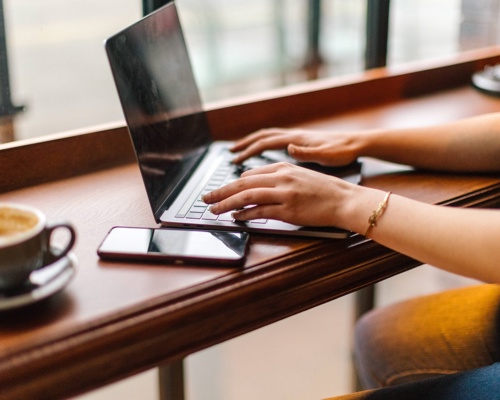 Woman writing on her laptop in a coffee shop