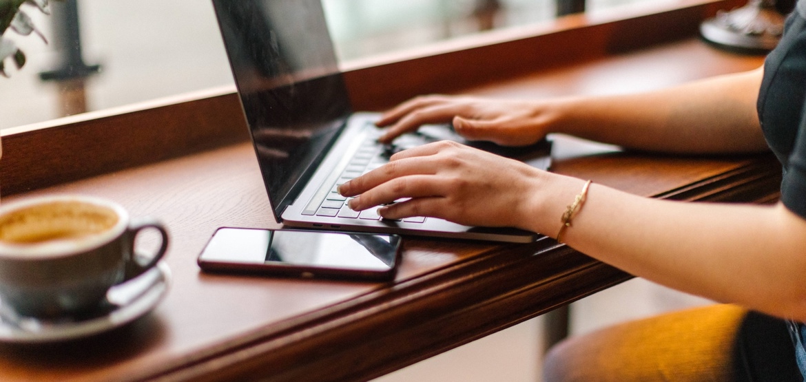 Woman writing on her laptop in a coffee shop