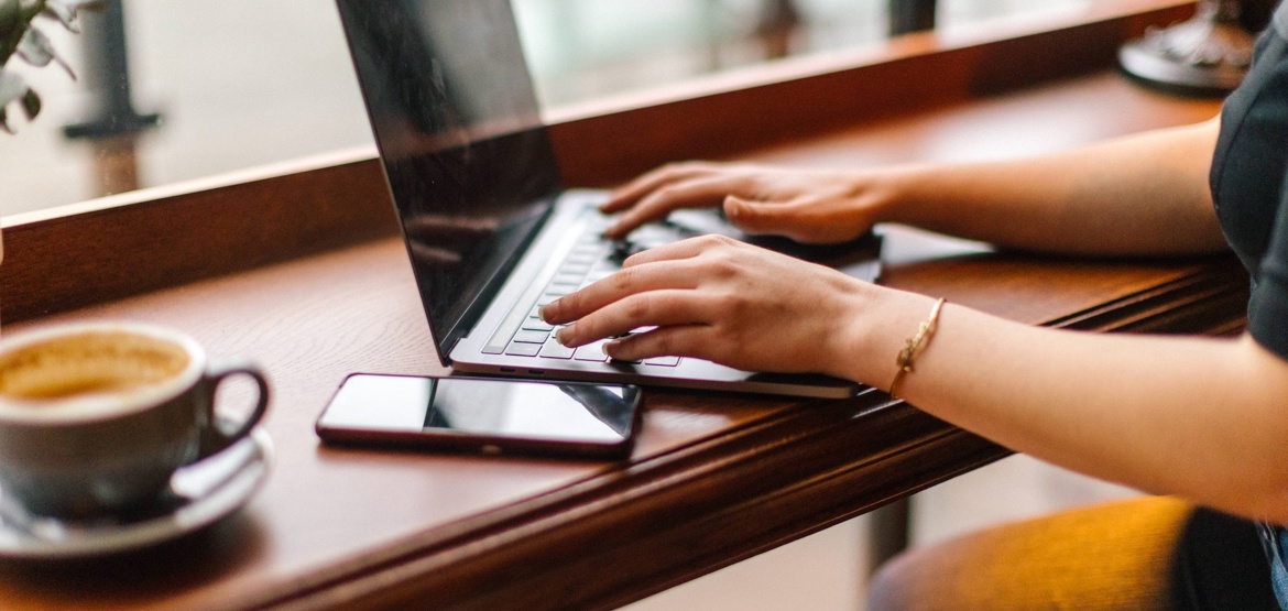Woman writing on her laptop in a coffee shop