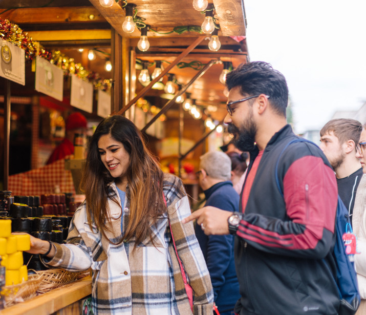 Asian man and woman looking at items on a food stall 
