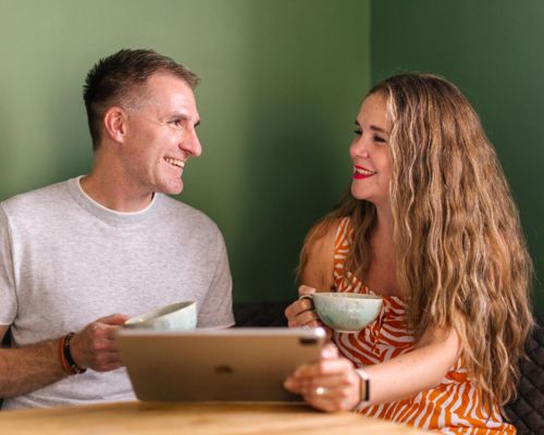 Couple holding coffee cups and an iPad.