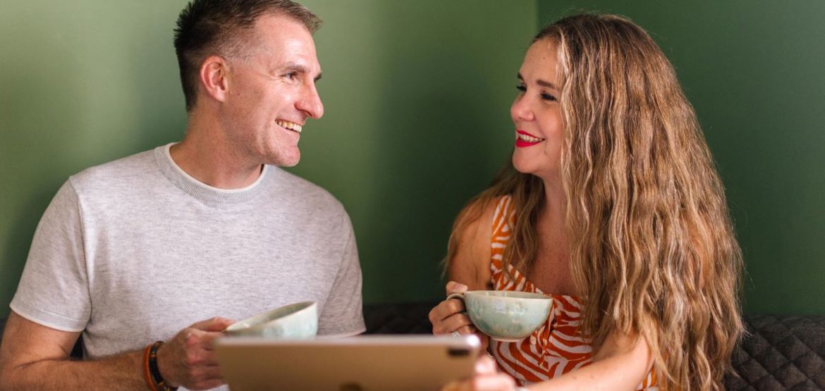 Couple holding coffee cups and an iPad.