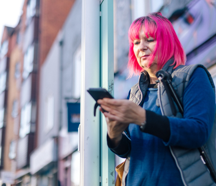 Woman waiting at a bus stop using her phone