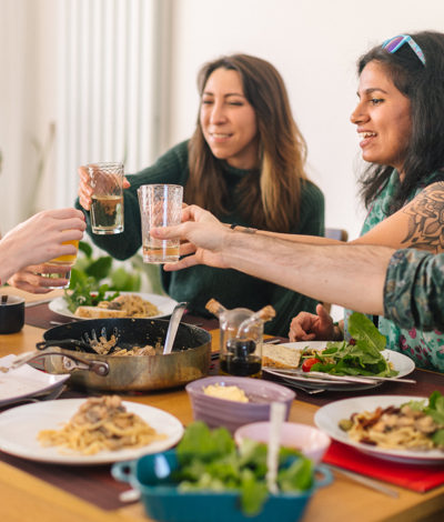 Group of people saying cheers around a dinner table with food