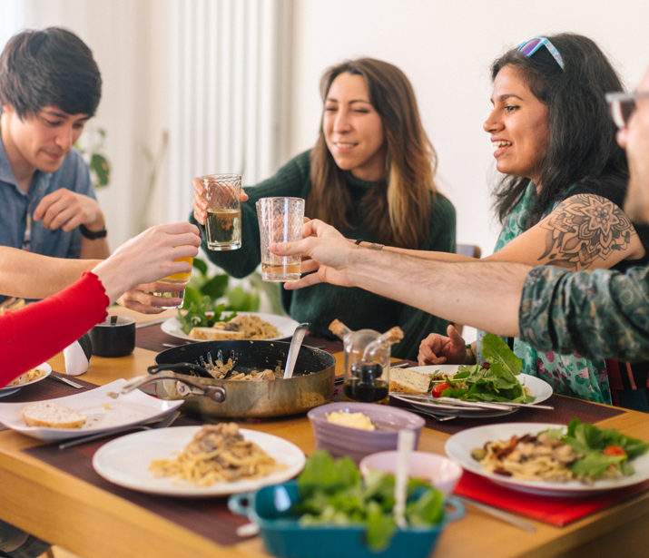 Group of people saying cheers around a dinner table with food