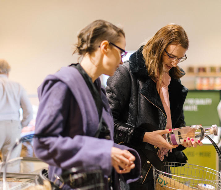 Two people shopping together, inspecting a bottle with a basket in hand
