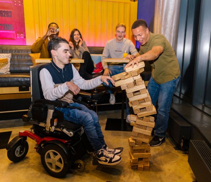 Friends playing giant Jenga in a games bar.
