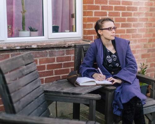 Woman sat on bench with notebook